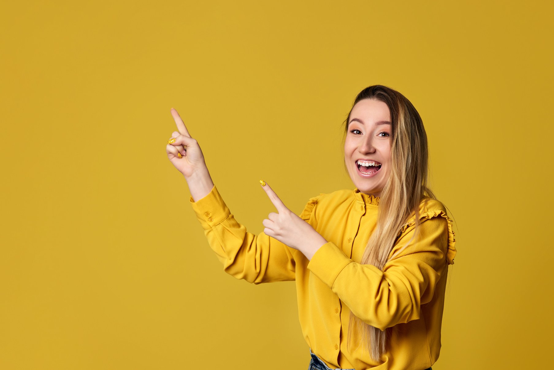 Young Woman Pointing Away on Yellow Background